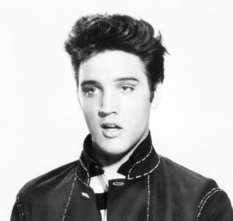 Elvis Presley appears in a 1957 image for Jailhouse Rock, wearing his signature upturned collar and pompadour hairstyle. 