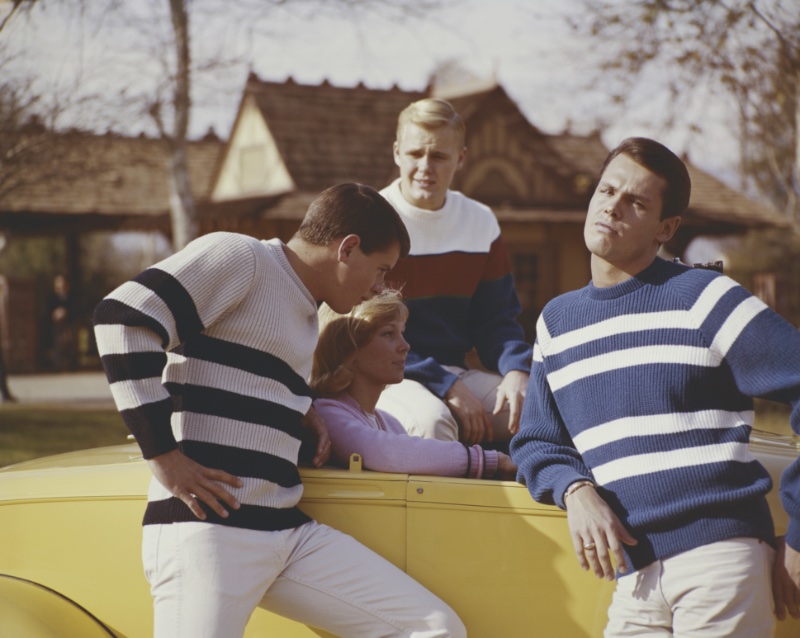 Young men wear striped sweaters evocative of sixties menswear trends. 