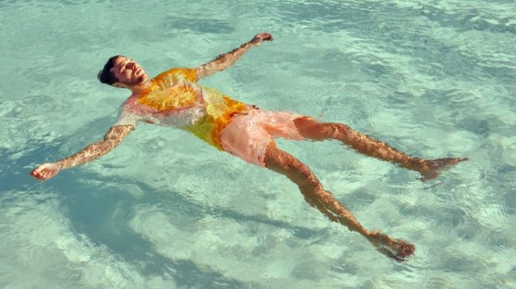 Relaxing in the pool, Arran Sly sports a tie dye t-shirt with garment dyed swim shorts from Scotch & Soda.